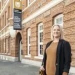 A Master of Business Administration (MBA) student standing in front of the Curtin Graduate School of Business.