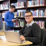 Mature-aged Curtin MBA student sitting in the library and looking up from his laptop