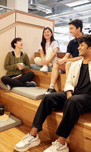 Group of four students sitting on stairs, smiling and laughing