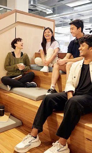 Group of four students sitting on stairs, smiling and laughing