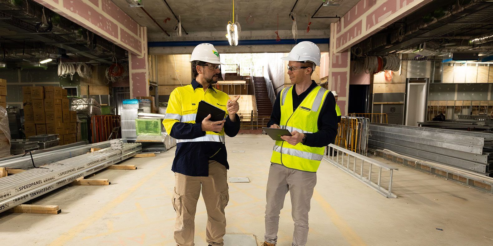 Two people in high-vis vests standing in a warehouse