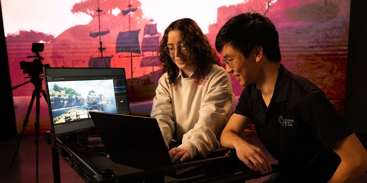 Two people looking at a laptop smiling.